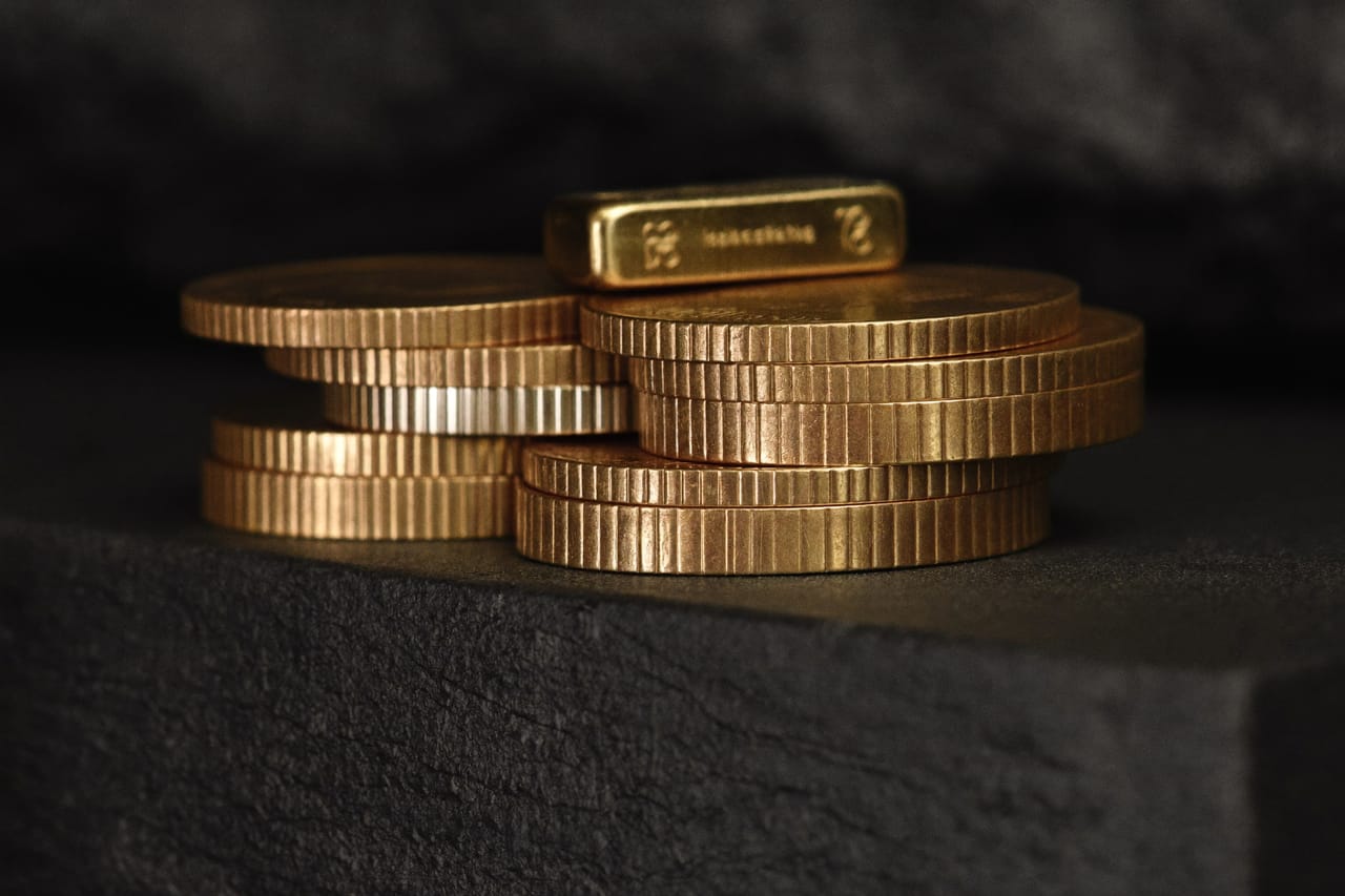 Gestapelte Goldmünzen von der Seite auf dunklem Stein